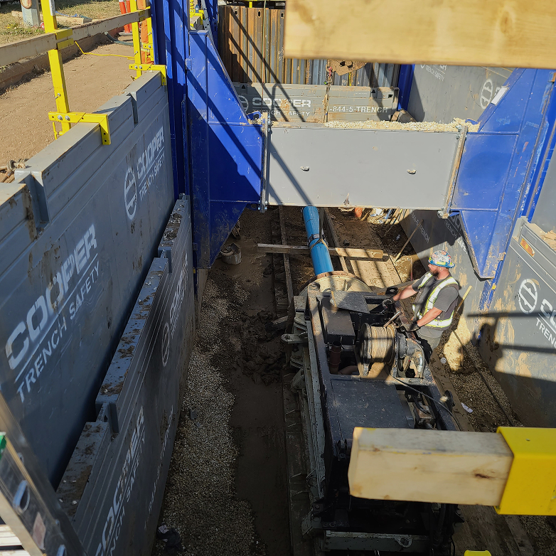 Trench shoring system with an auger boring machine and worker inside the pit